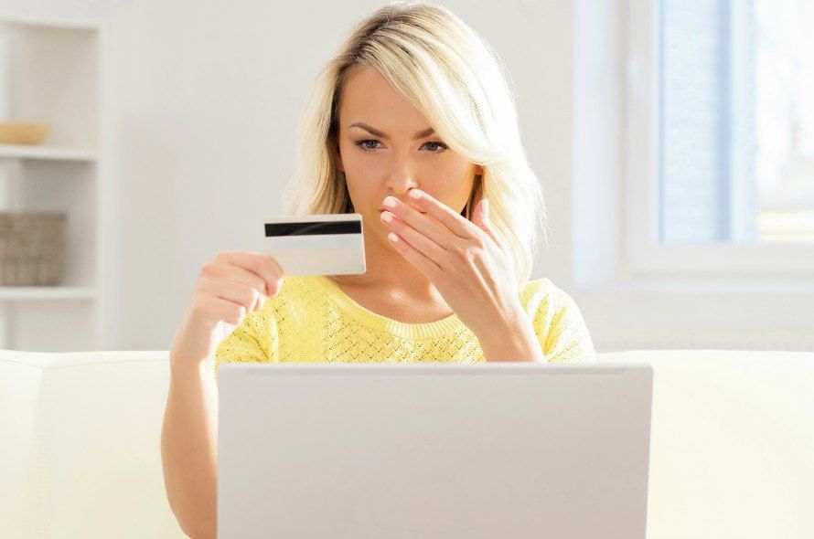 クレジットカードを見つめて口をふさぐ女性