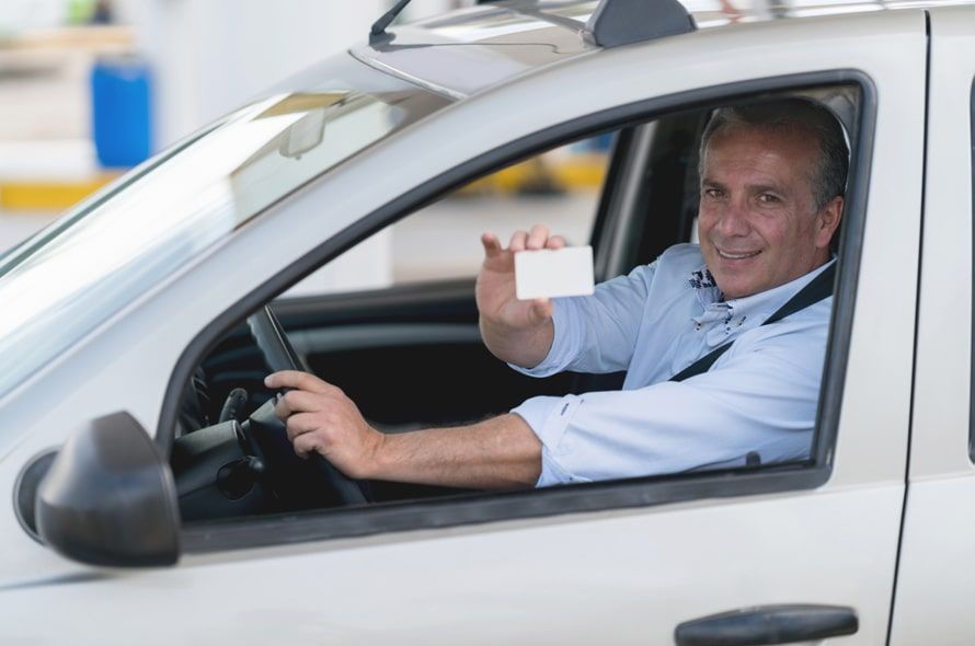車に乗ってカードを見せる男性