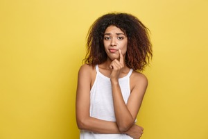 黄色い壁にもたれて悩む女性