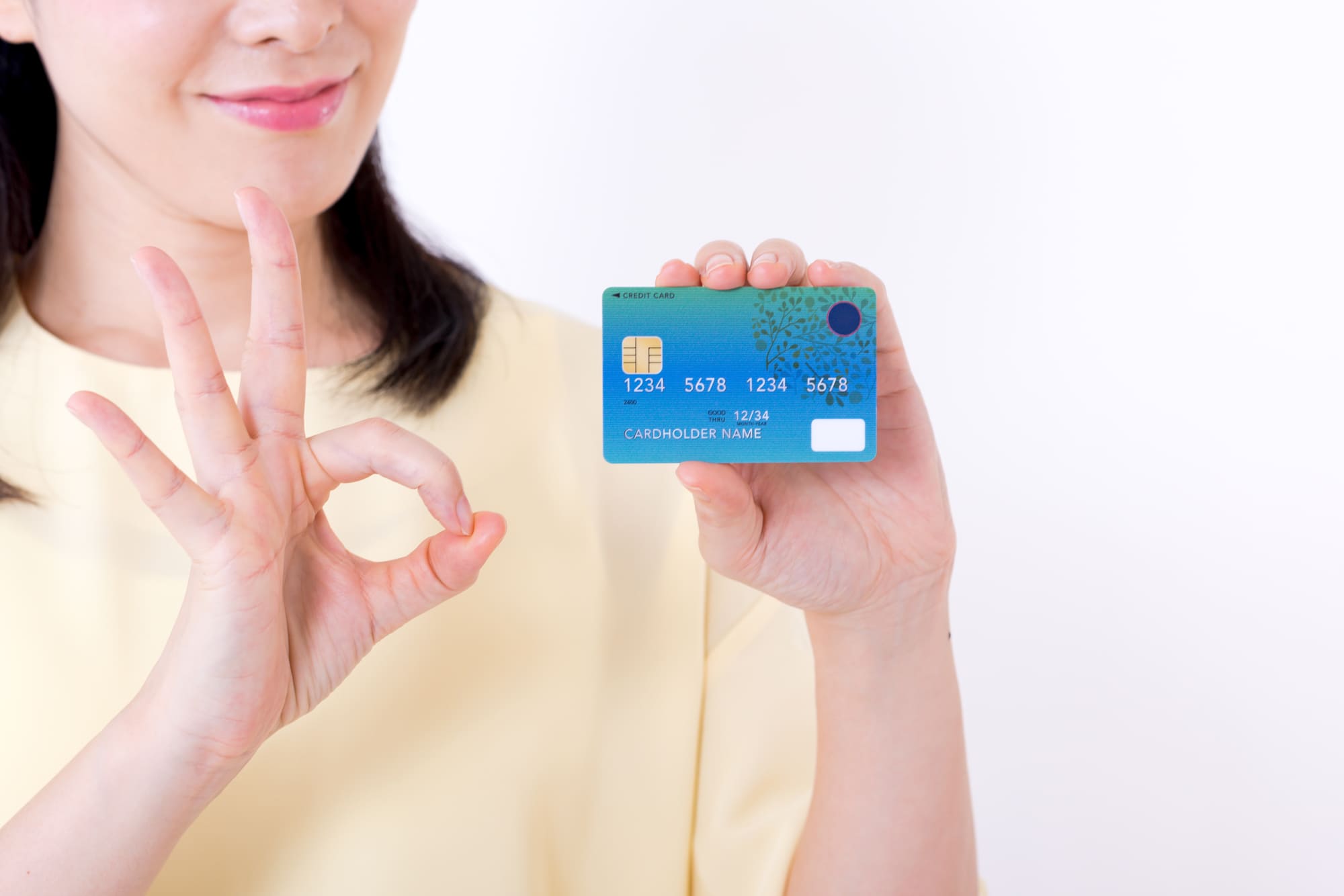 クレジットカードを持ってOKサインをしている