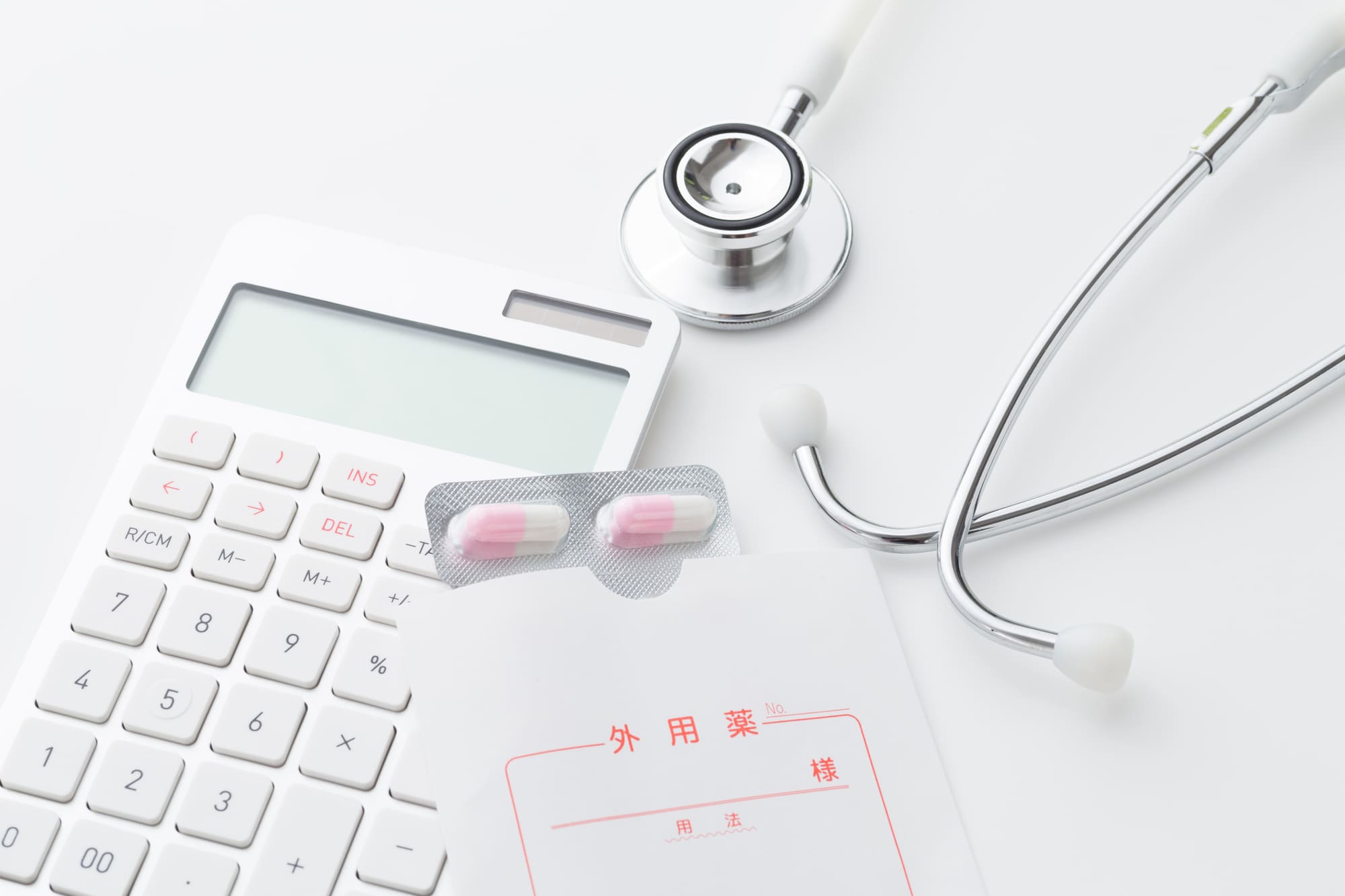 白い背景に聴診器と薬と電卓