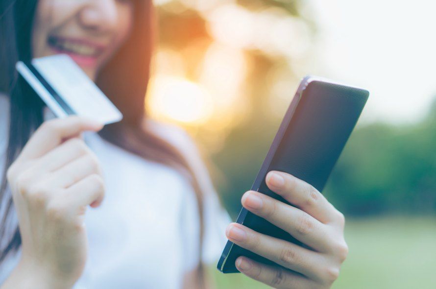 カードを持ちながらスマホを触る女性